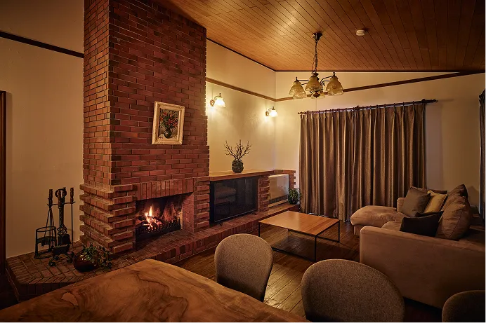 Living room under a wood-paneled ceiling, warmed by the fireplace