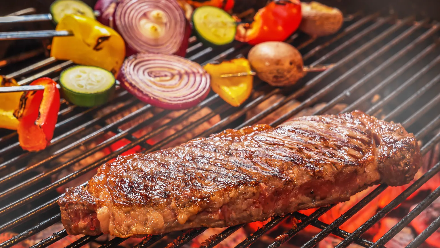 Steak and vegetable skewers grilling over the fire