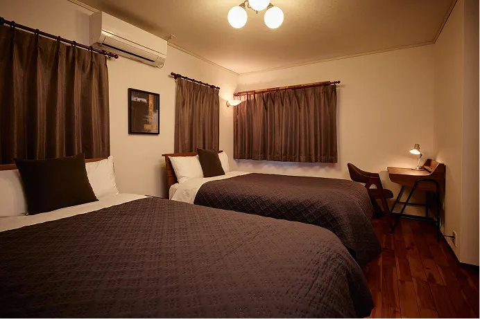 Bedroom with two beds and a small desk beside the window