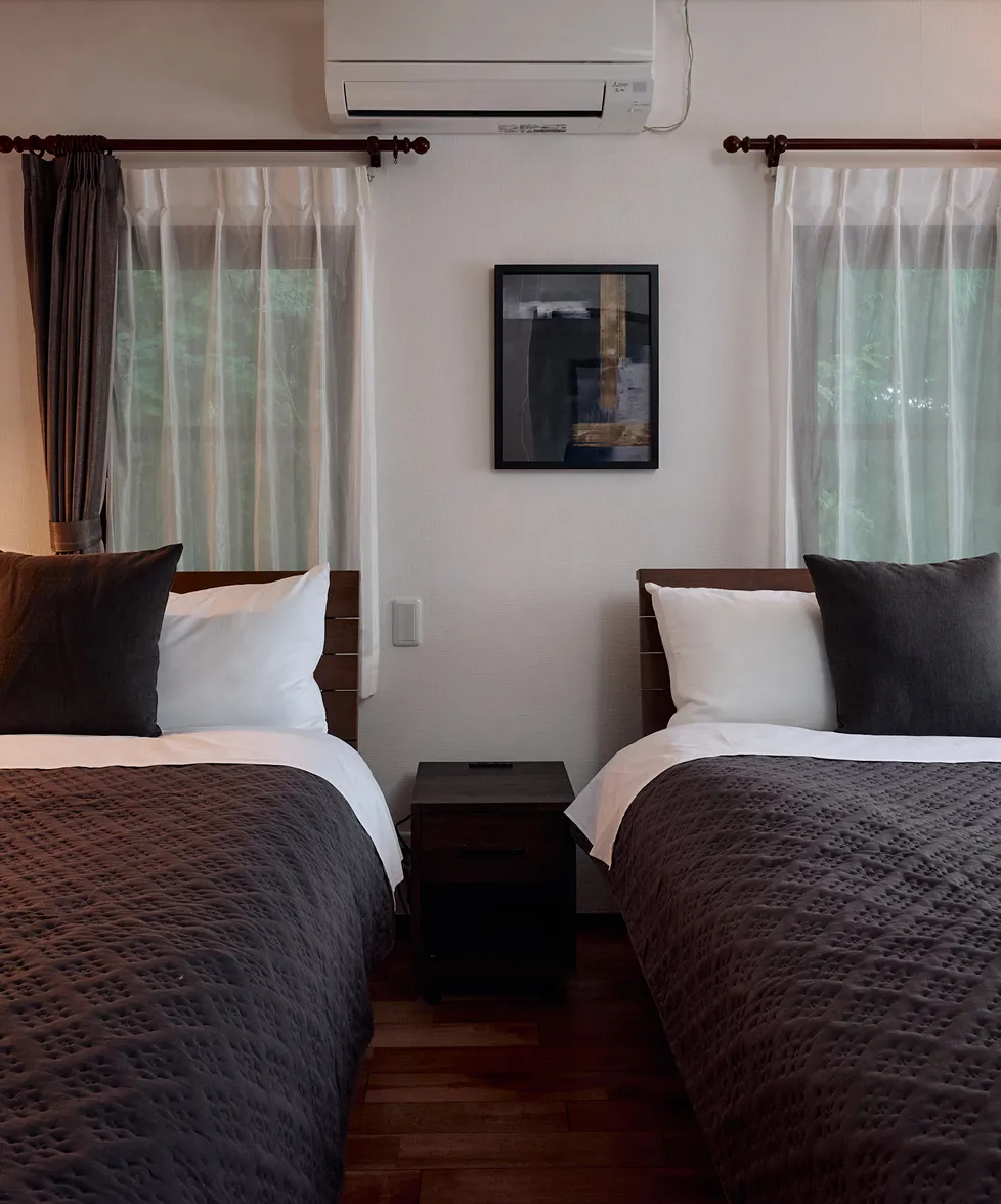 Two beds set between the windows, with framed art on the wall