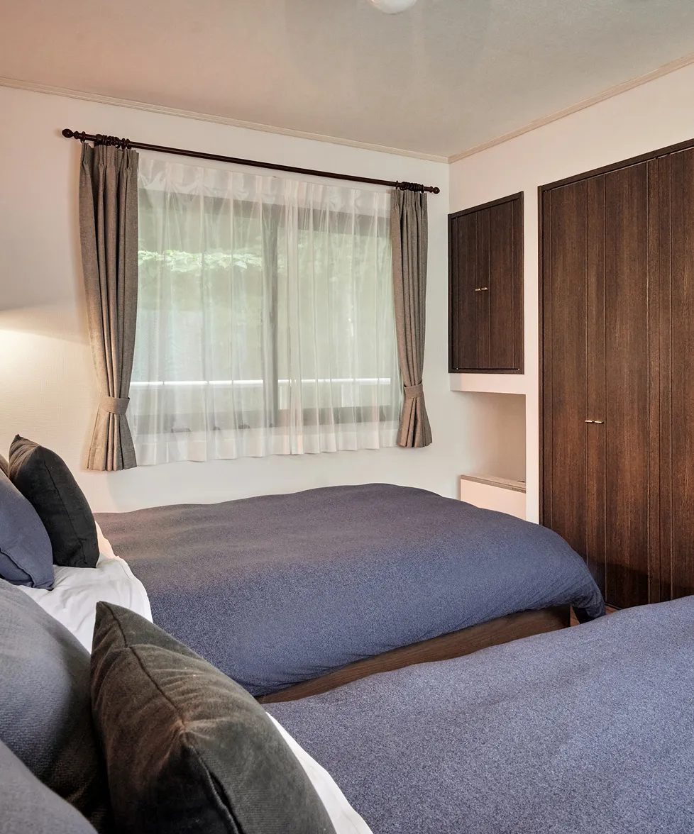 Bed by the window with a wooden wardrobe alongside