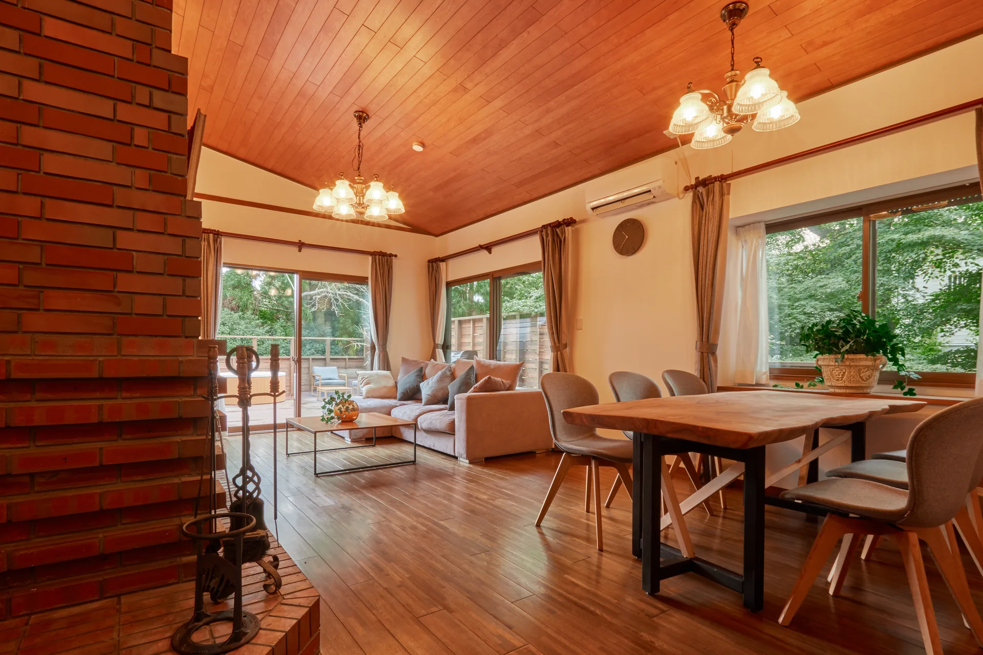 Living-dining room with a brick fireplace and vaulted wooden ceiling