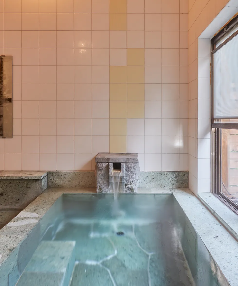 Hot spring water flowing from the stone spout into the bath