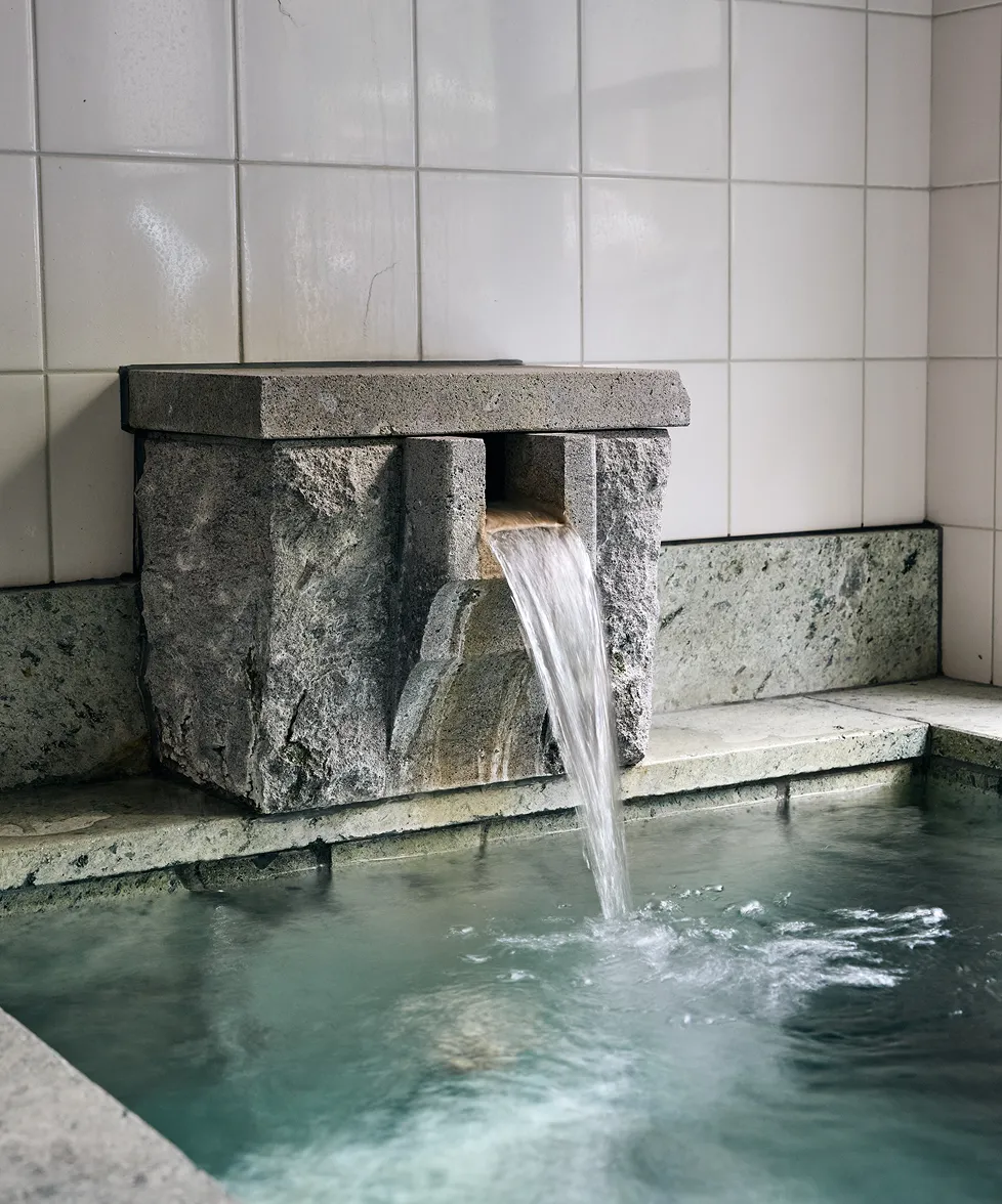 Close-up of the stone spout pouring free-flowing hot spring water