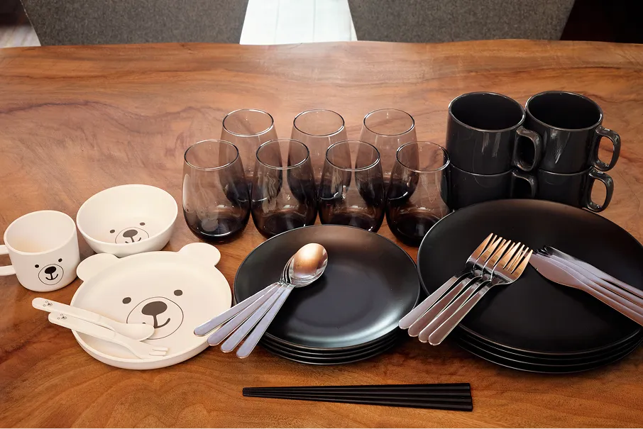 Plates, bowls, glasses, mugs, and cutlery laid out on the table