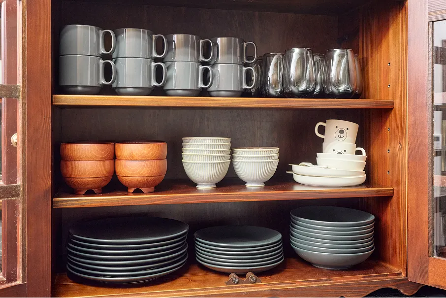 Cupboard shelves stocked with mugs, glasses, bowls, and plates