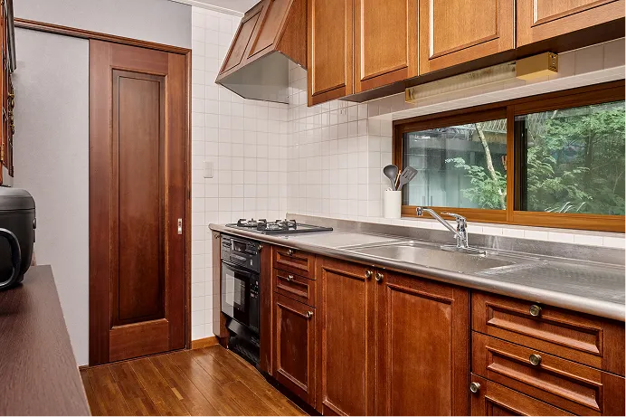 Kitchen in warm wood with a stainless counter and a window onto the trees