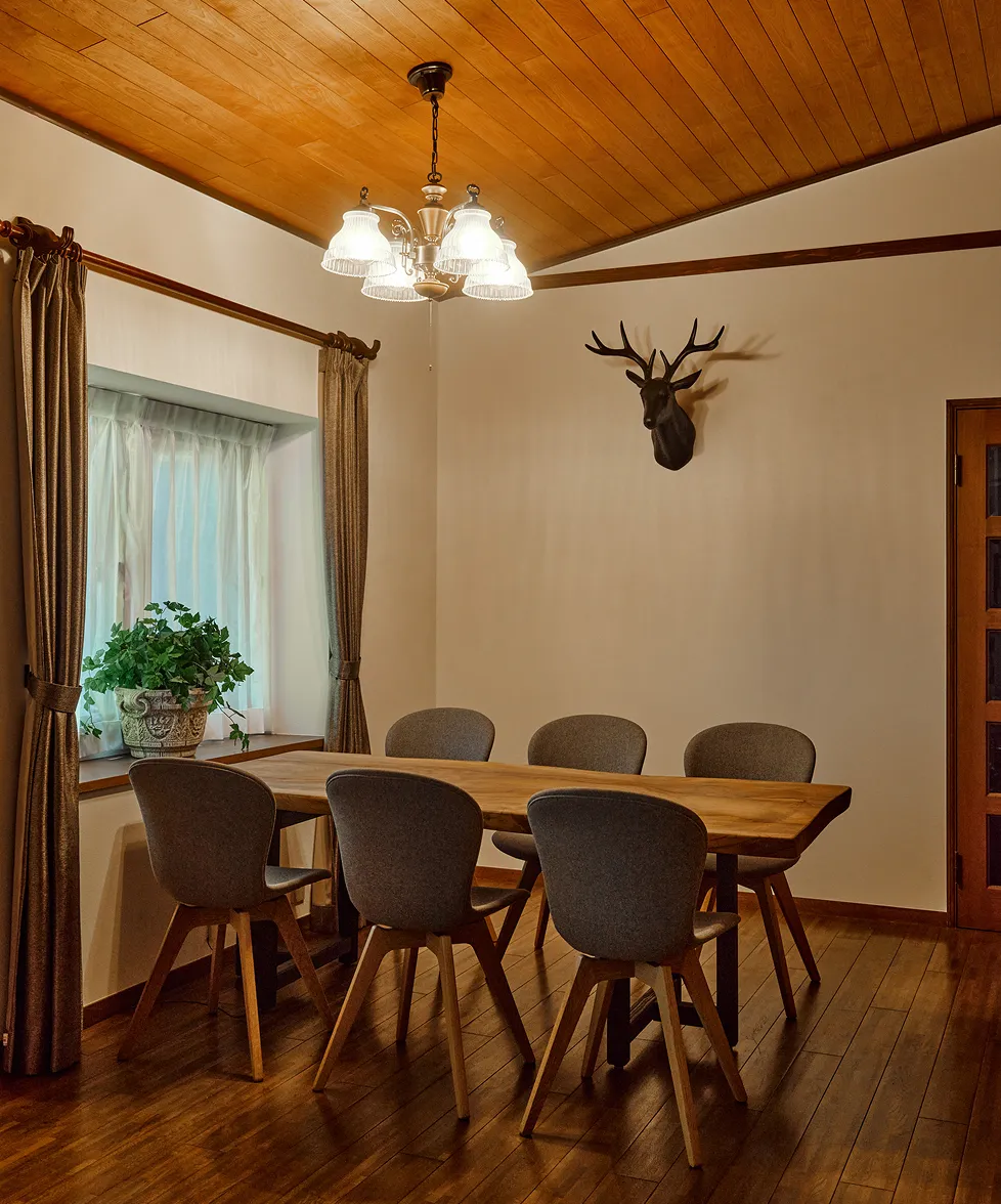 Dining table set with six chairs beneath the wood-paneled ceiling