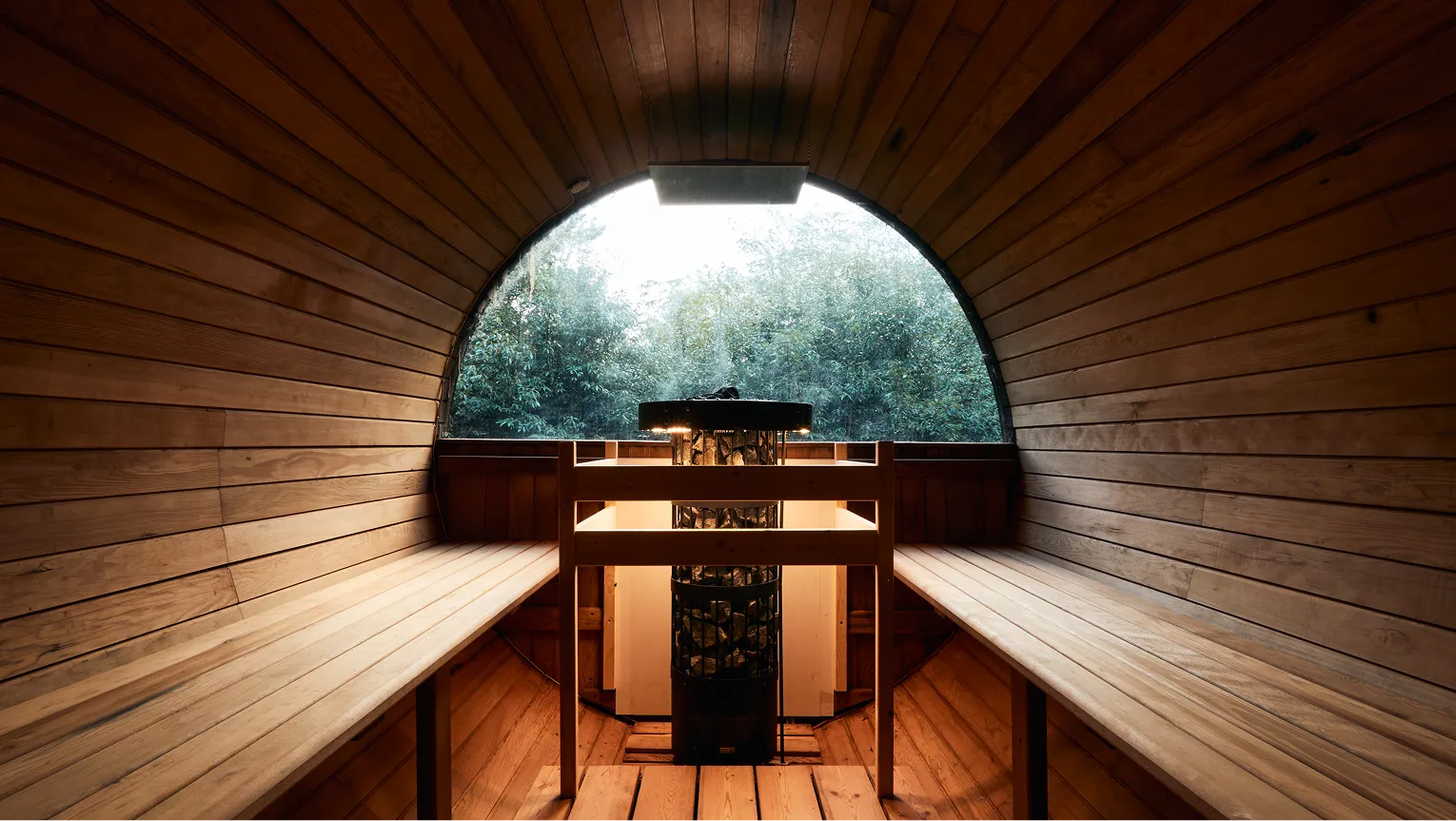 Inside the barrel sauna, looking out through the arched window to the trees