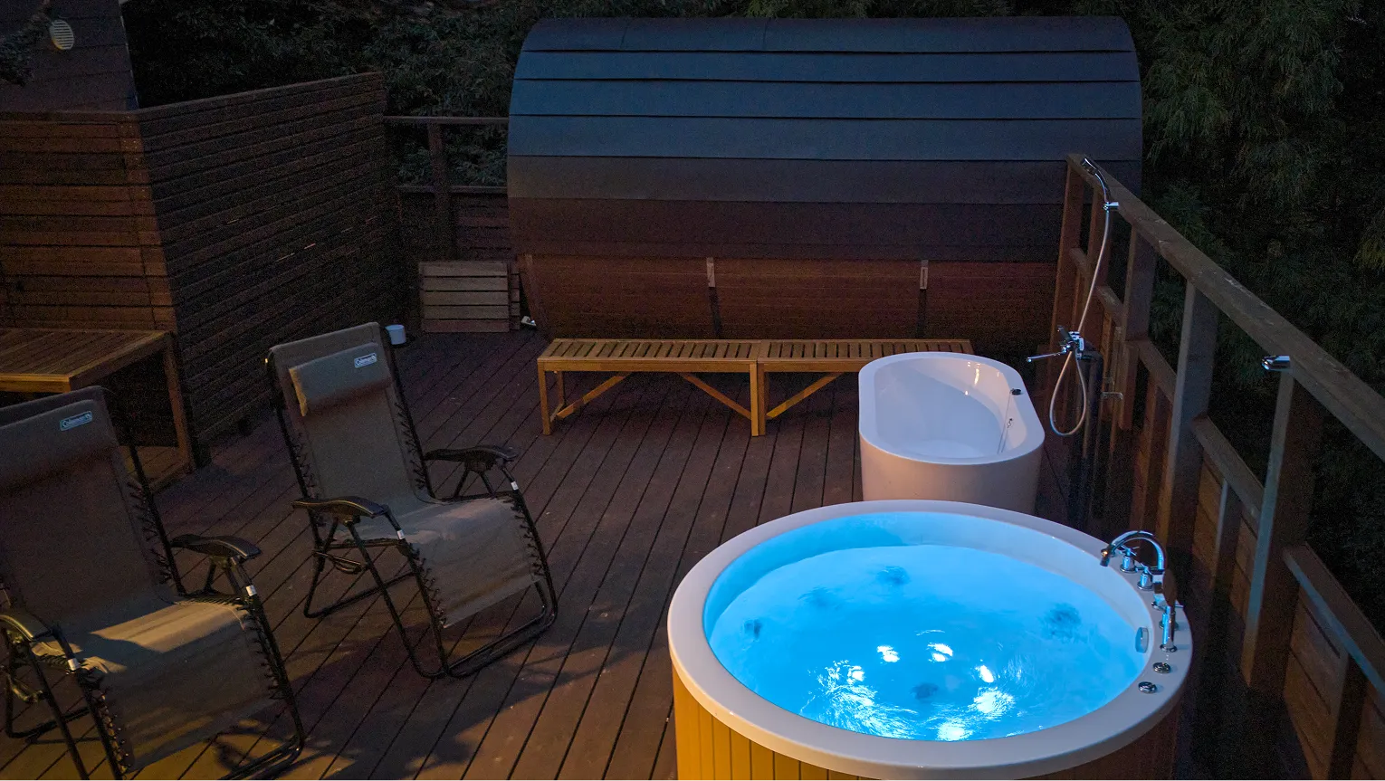 Jacuzzi glowing on the evening deck beside the barrel sauna