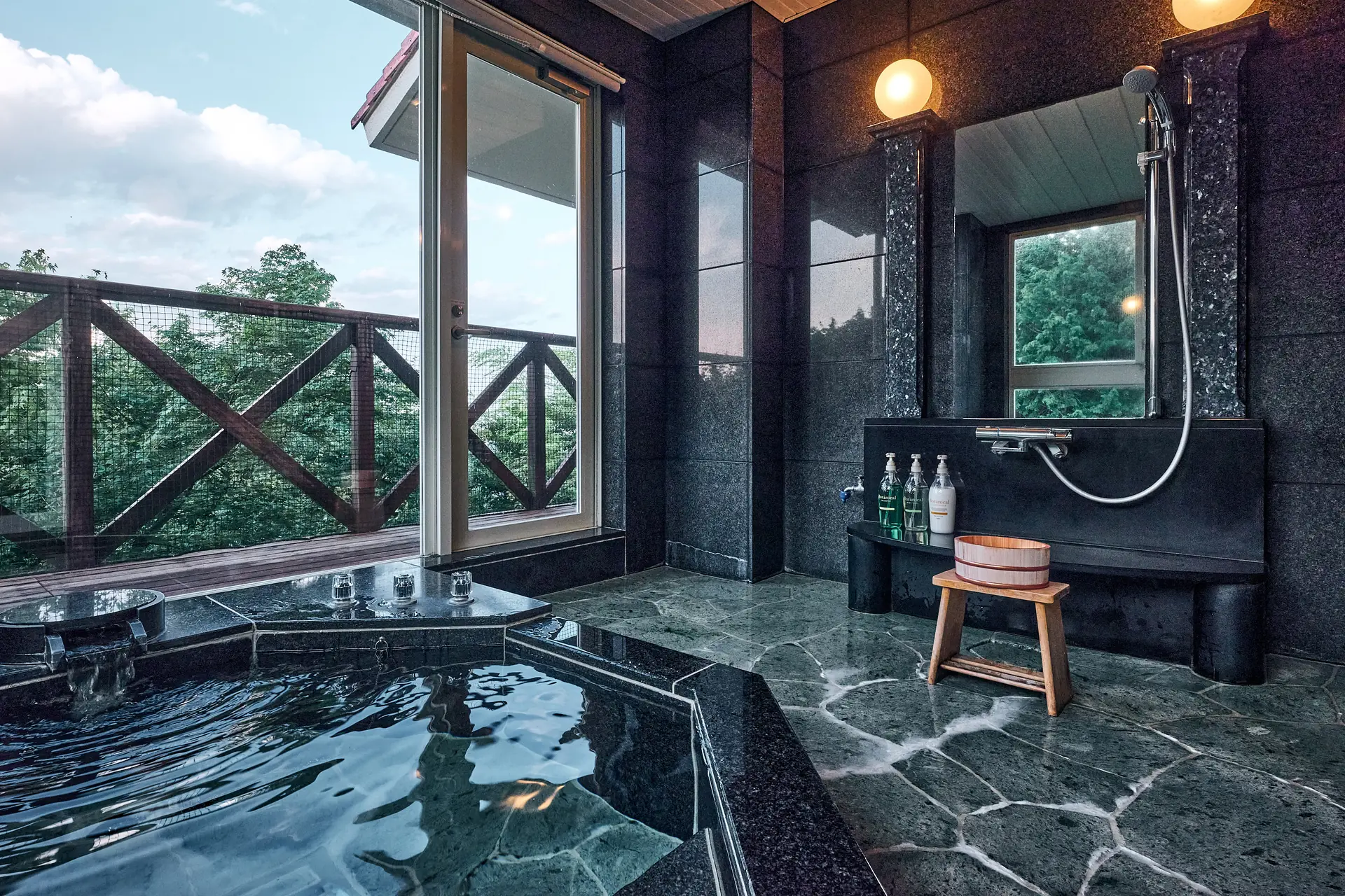 Stone onsen bath looking out on the Hakone forest through a wide window
