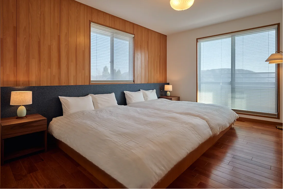 Western-style bedroom wrapped in gentle wood tones with two double beds
