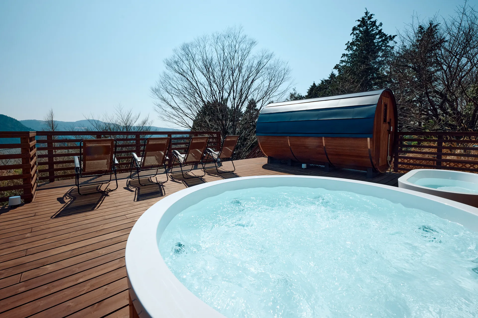 Bubbling jacuzzi and barrel sauna under a clear sky