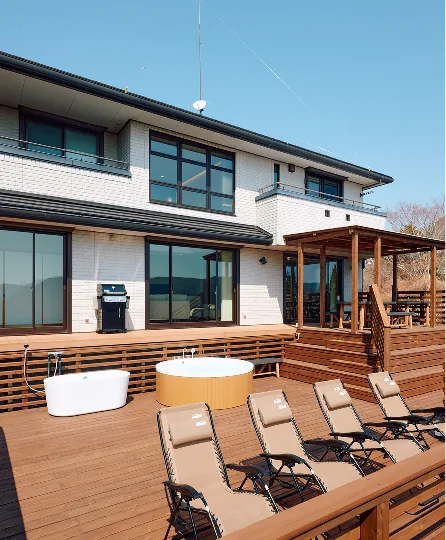 Wooden deck with bathtubs and loungers in front of the villa