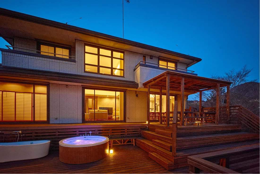 The villa at night with its lit jacuzzi on the deck
