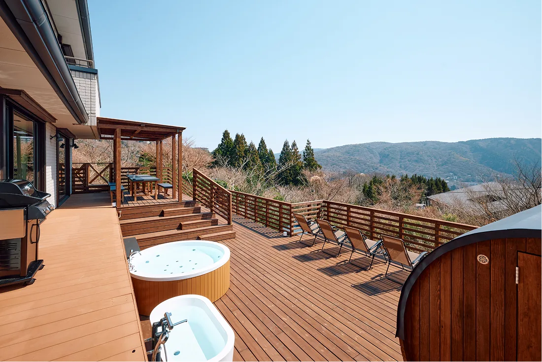 Bathtub and jacuzzi lined up on the deck with mountain views