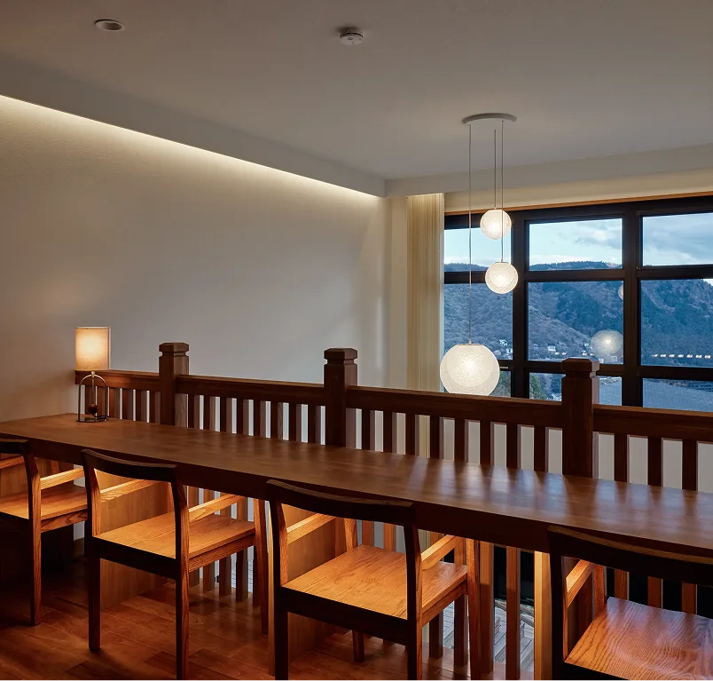 Long wooden table and chairs by the window overlooking Lake Ashi