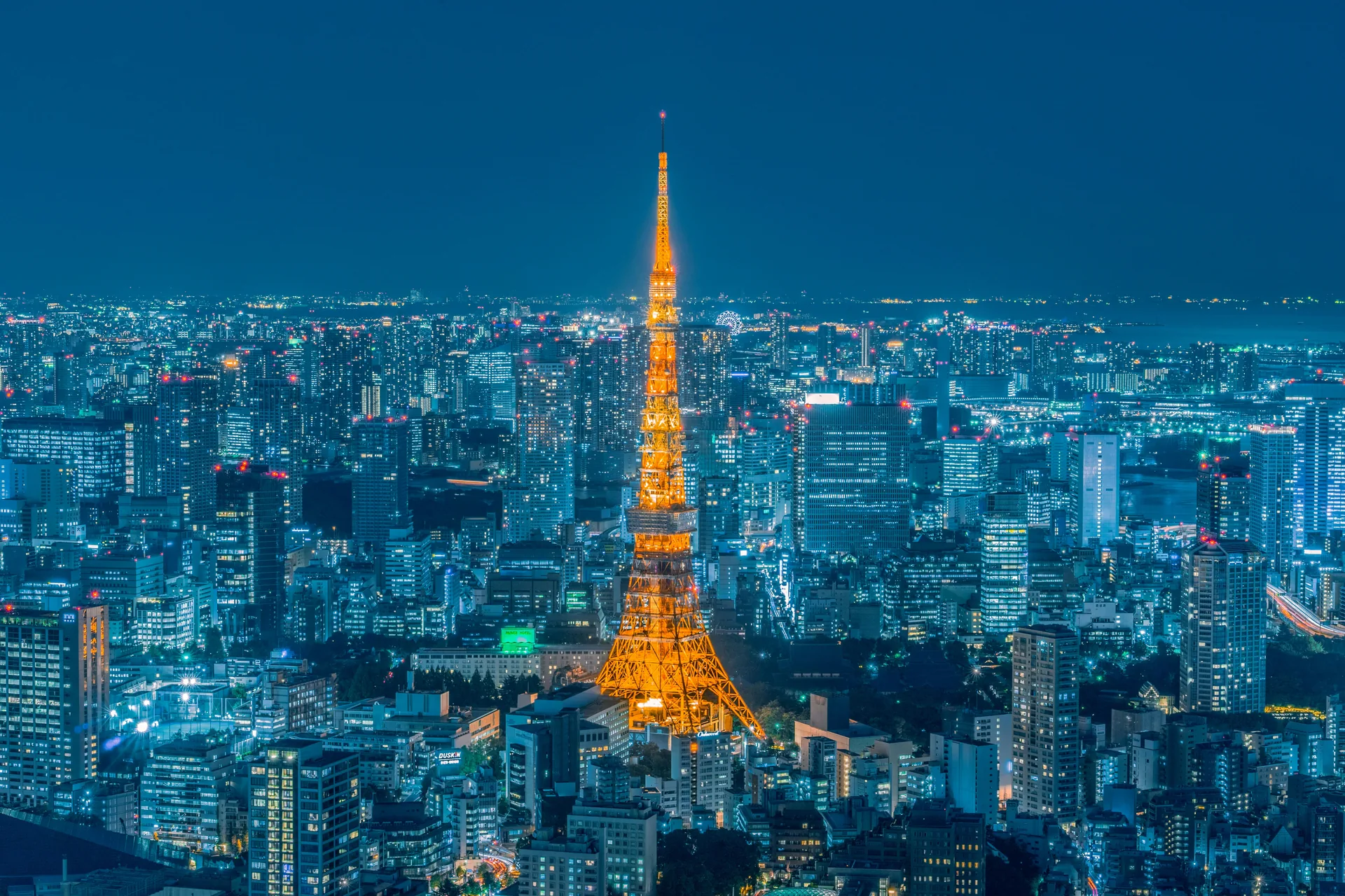 Tokyo Tower glowing gold above the sparkling city lights at dusk