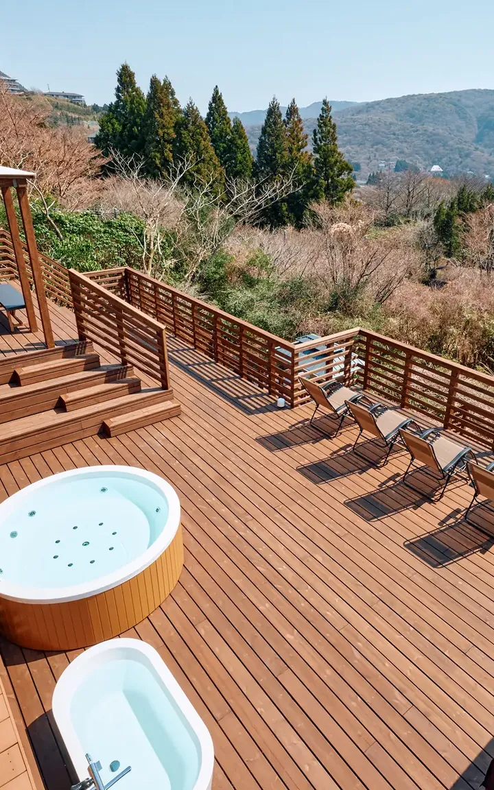 A wide wooden deck with a jacuzzi, overlooking the mountains
