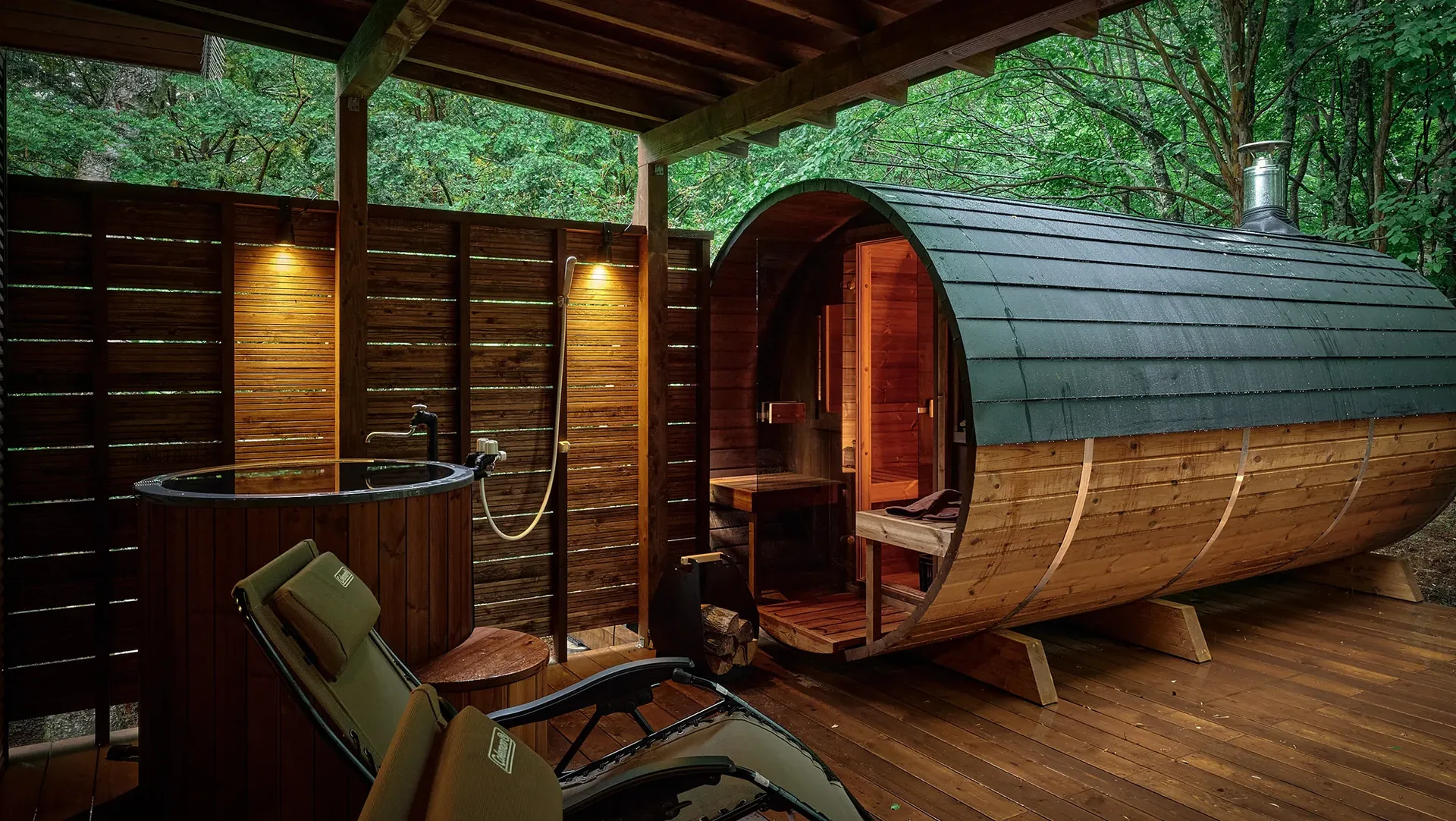 Barrel sauna and cold plunge tub on a wooden deck in the forest